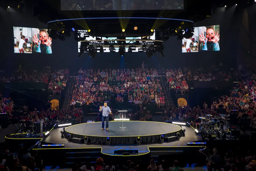 Speaker on a round center stage before a full arena