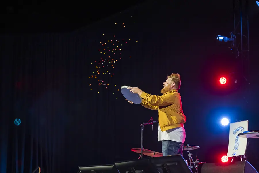 Performer tossing confetti under stage lights