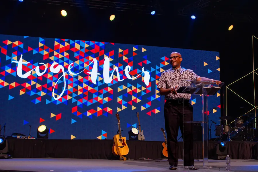 Speaker beside a large patterned conference stage screen