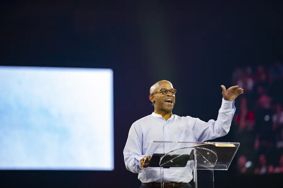 Speaker addressing a conference audience with an open gesture