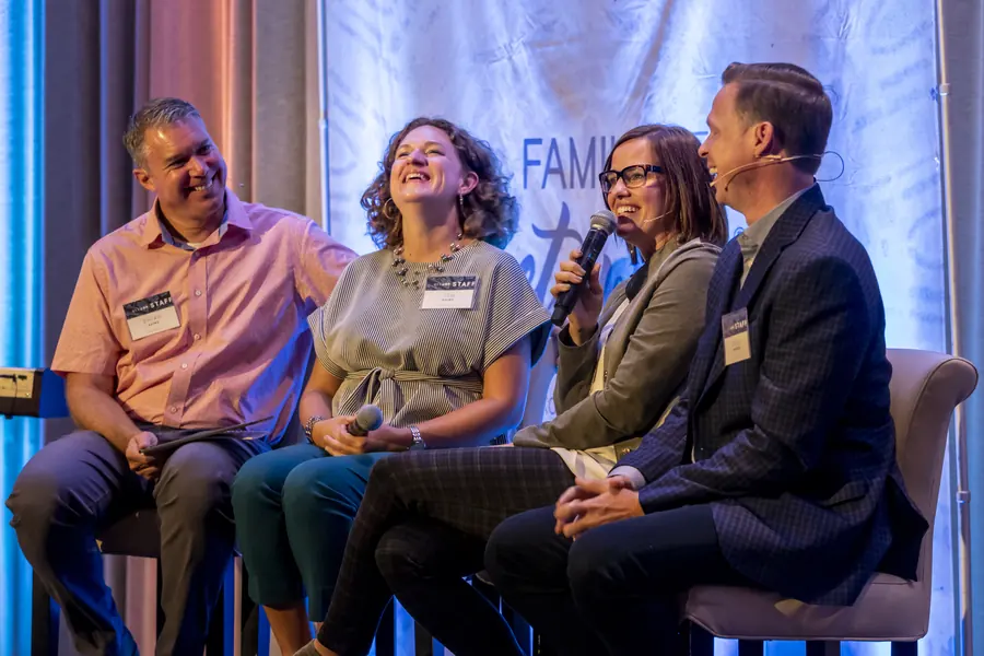 Panel of speakers laughing together on stage
