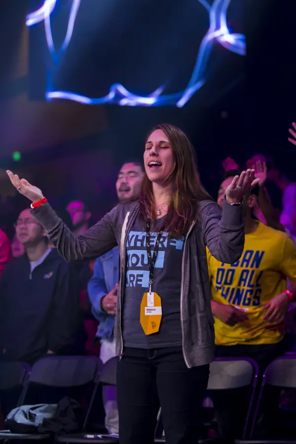 Attendee with hands raised during a session