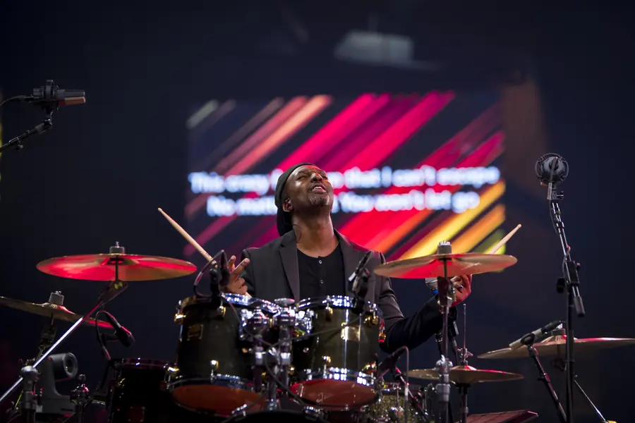 Drummer framed within the kit against a lit backdrop