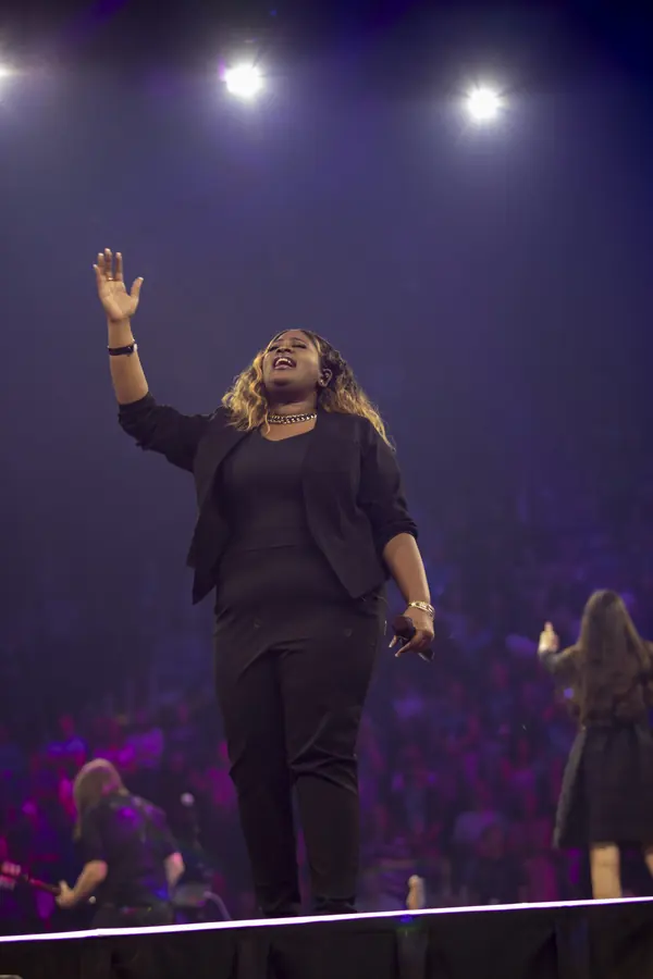 Singer with hands raised in purple stage light