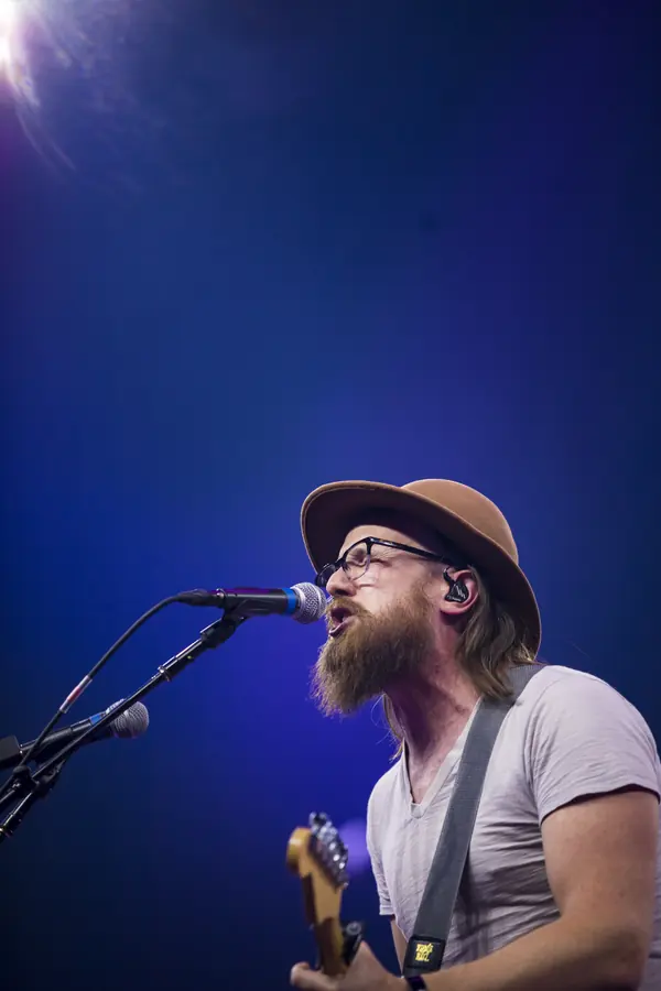 Singer in a hat performing under blue stage light