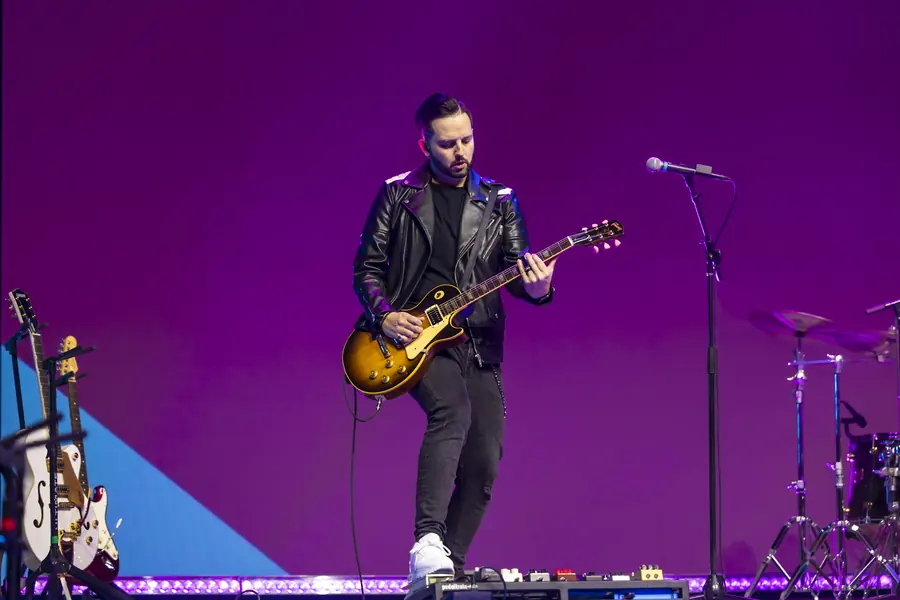 Guitarist performing against a bold graphic stage backdrop