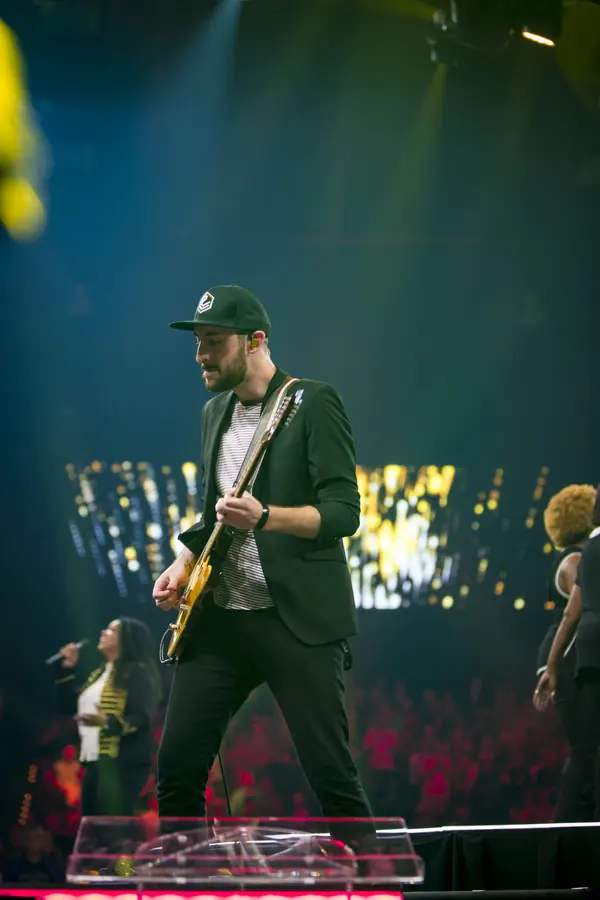 Performer on stage in green light with a sparkling backdrop