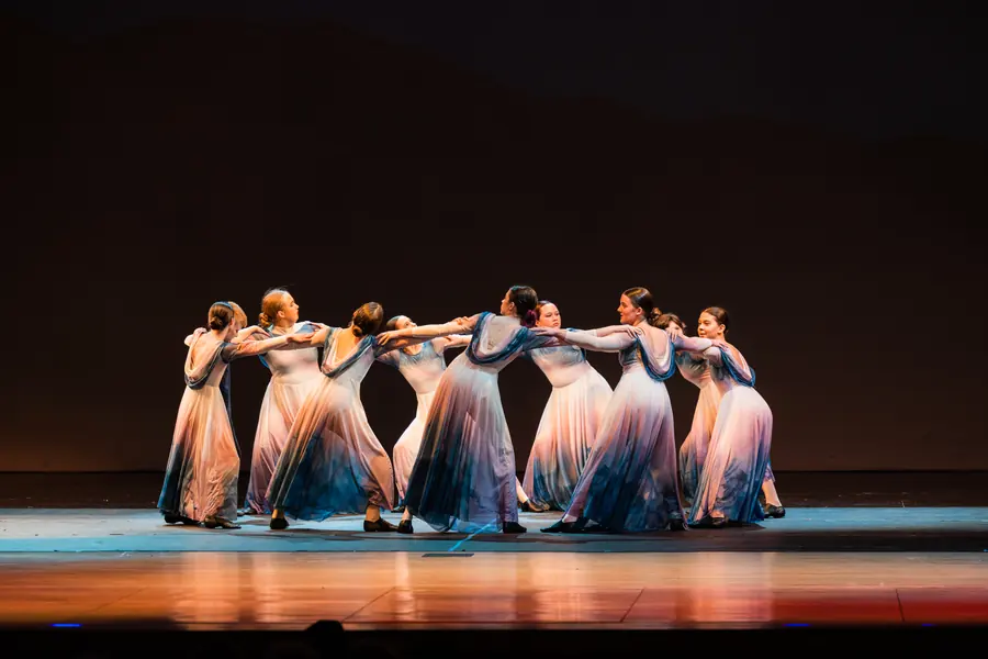 Dancers in flowing blue costume mid-motion