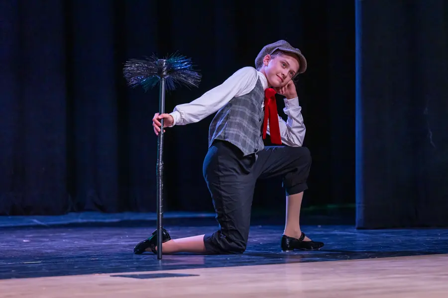 Young dancer in a chimney-sweep costume under blue light
