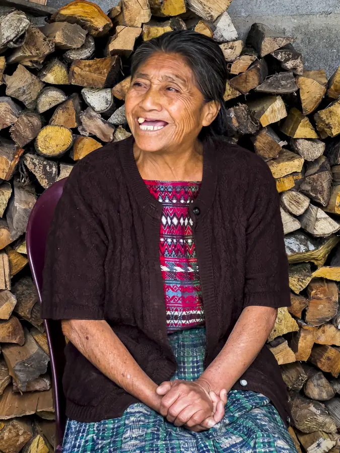 Woman seated against a stack of firewood, Guatemala