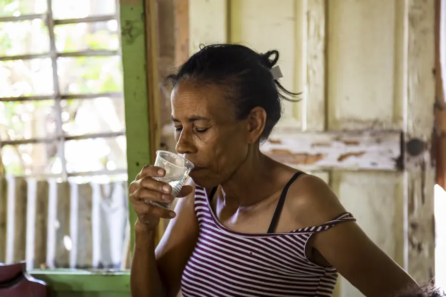 Woman drinking clean water at home after receiving a filter