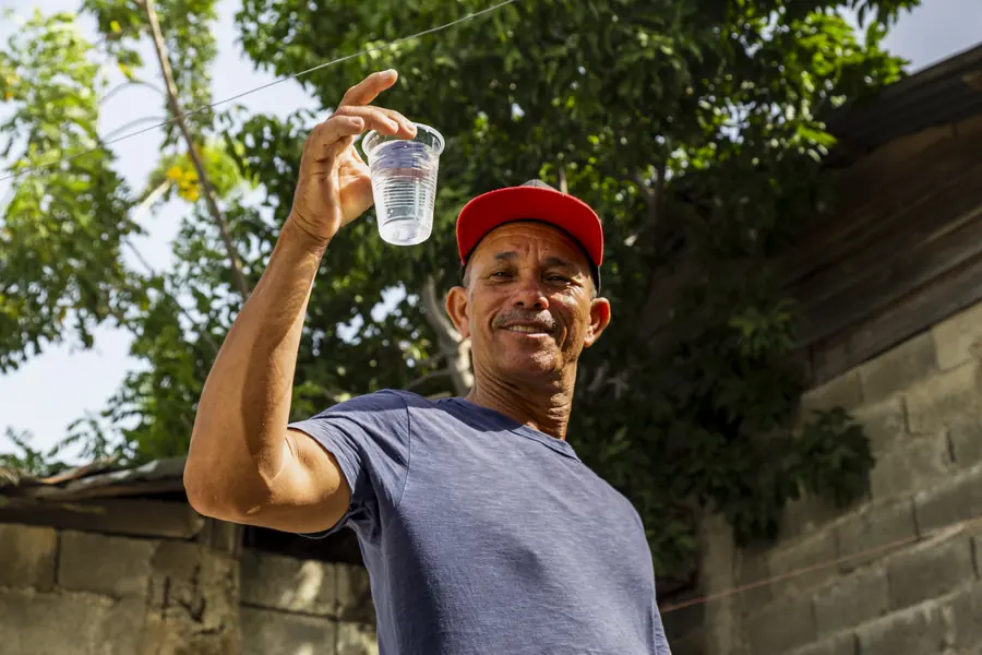 Man holding up a glass of clean water outdoors